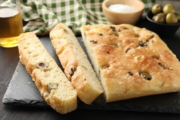 Pieces of delicious focaccia bread with olives and thyme on dark wooden table, closeup