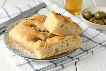 Slices of delicious focaccia bread with olives, thyme and salt on white wooden table, closeup