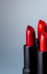 Obraz premium Trio of cosmetic lipsticks in classic red shades with sleek black packaging.