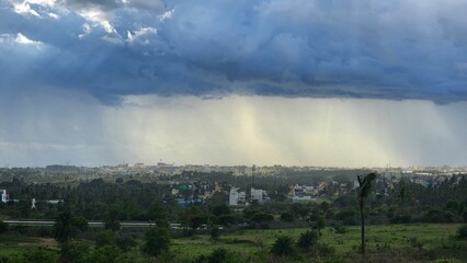 Cityscape under dramatic sky with rain clouds and sunlight.