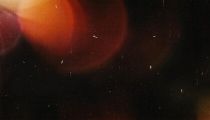 Abstract cinematic bokeh texture with warm red and orange light flares on a black background, vintage film grain overlay effect