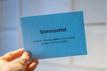 Holding an envelope with the title "Stimmzettel" (ballot paper) for a voting in Germany. Political election or a works council for example.