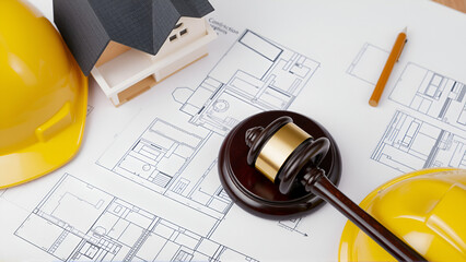 A courtroom gavel resting on architectural drawings, with a yellow hard hat and a house model, emphasizing the legal aspects of construction.