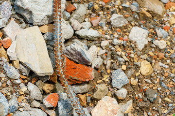 Old rusty metal fittings against a background of piles of stones and other construction debris. Construction background.