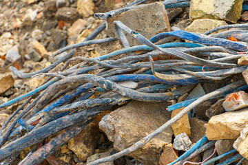 An old electrical cable sticks out of the ground against a backdrop of bricks and construction debris.