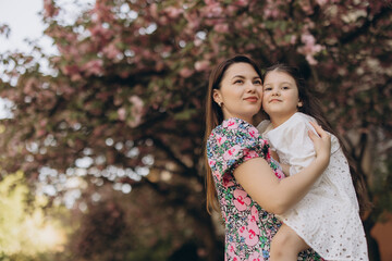 Mother embracing daughter in blooming garden celebrating mother's day