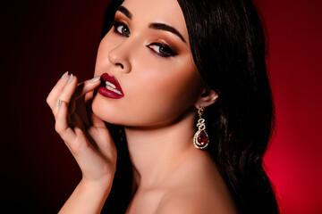 Close up cropped profile portrait of hot model woman finger touch lips isolated on dark burgundy...