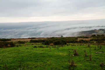 Temperature Inversion with clouds hugging valleys and hills green moor in foreground.