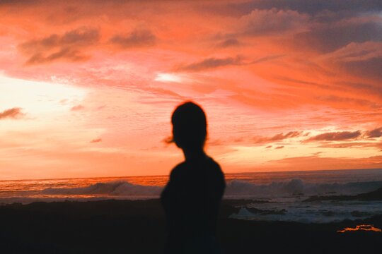 Silhouette of Woman Watching Dramatic Sunset Over Mountain Landscape