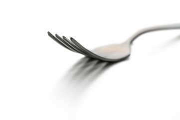 Elegant silver fork resting on a reflective surface with soft lighting creating delicate shadows