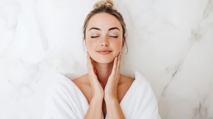 Fototapeta premium A serene woman in a robe gently touches her face, exuding a sense of relaxation and self-care against a marble background.