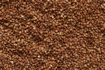 Buckwheat groats, top view. Raw large buckwheat grains, uncooked porridge. Buckwheat background. Raw buckwheat texture background, brown grains pattern