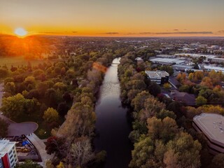 Sunset over a city river, showcasing a mix of parks, buildings, and trees. Aerial view of urban landscape. Boise River, Boise, Idaho, USA.