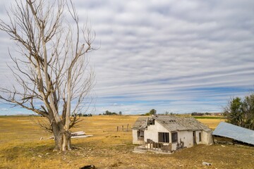 Abandoned farmhouse in a rural field. Deteriorating structure, dry, barren landscape. Nature...