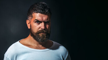 Fototapeta premium Man portrait. Handsome bearded man in white t-shirt. Serious man with beard and mustache in casual clothes. Confident pensive male model with stylish hairstyle. Copy space for barbershop advertising.