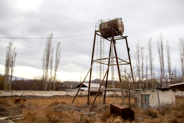 Old rusty water tower in abandoned rural area