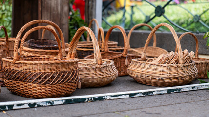 Obraz premium A collection of handcrafted wicker baskets displayed outdoors on a wooden surface. The intricate designs highlight traditional craftsmanship and natural materials.