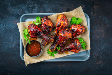 Authentical barbecue chicken drumsticks with hot chili sauce as marinade and coriander leaves...