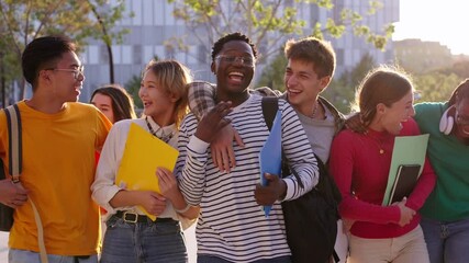 Group of generation z international university students laughing walking hugging together on campus. Young diverse people looking surprised at each other holding backpacks and workbooks outdoors - Powered by Adobe