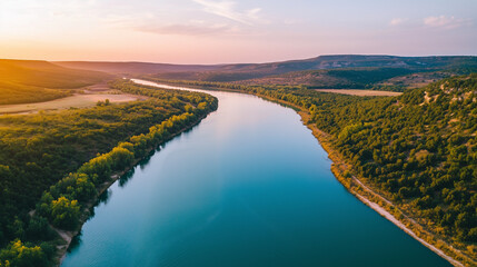 A breathtaking aerial view of a serene river winding through a lush, green landscape surrounded by rolling hills, illuminated by the warm hues of a setting sun