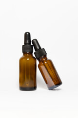 Two amber glass medicine bottles, one leaning on the other on a white background