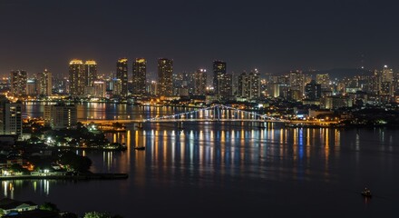 Fototapeta premium Stunning Nighttime Cityscape with Illuminated Skyscrapers Reflected on Water Surface, Showcasing Vibrant Urban Skyline and Twinkling Lights Across the Horizon