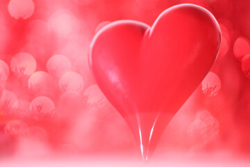 A vibrant pink background with a prominent red heart in the foreground, surrounded by soft bokeh...