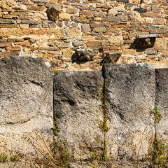 an ancient fence of large huge stones behind which is a stone ancient structure. copy space.