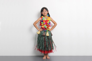 5 year old Latina brunette girl with glasses and Hawaiian skirt enjoys dancing and does Hawaii dance steps very happy and excited