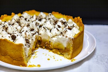 Traditional banoffee cake with banana and caramel sauce filling sprinkled with grated dark chocolate and coffee . English traditional pie