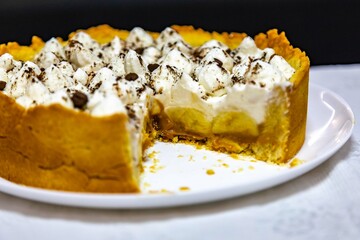 Traditional banoffee cake with banana and caramel sauce filling sprinkled with grated dark chocolate and coffee . English traditional pie