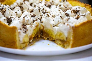 Traditional banoffee cake with banana and caramel sauce filling sprinkled with grated dark chocolate and coffee . English traditional pie