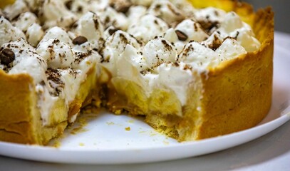 Traditional banoffee cake with banana and caramel sauce filling sprinkled with grated dark chocolate and coffee . English traditional pie