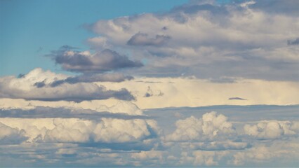 A vast sky filled with fluffy white clouds over a rural landscape.