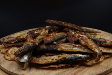 Fried fish served on a rustic wooden plate.
