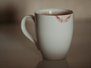 White cup with traces of red female lipstick. Lip imprint on an empty white cup of tea or drink. The camera moves across the background from top to bottom and stops on the cup. Date concept. Love idea