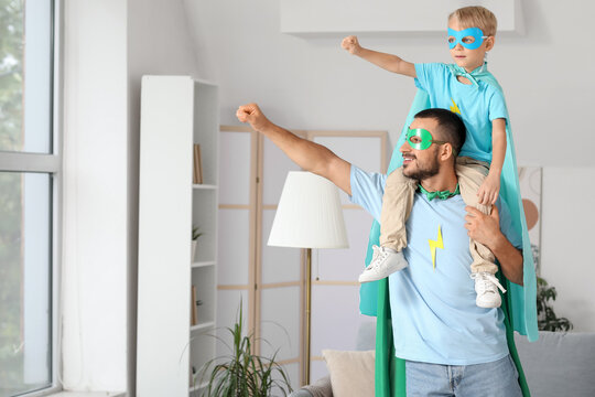 Happy father with his little son dressed as superheroes having fun at home