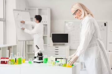 Female chemist with flasks on table in laboratory