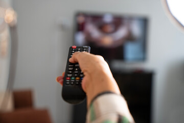 Mature woman holding the TV remote while watching television at home