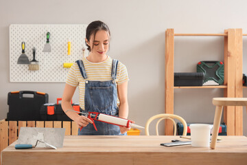 Obraz premium Young woman with sealant at table in room