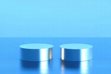 Two metallic cylinders on a reflective surface with a blue background.