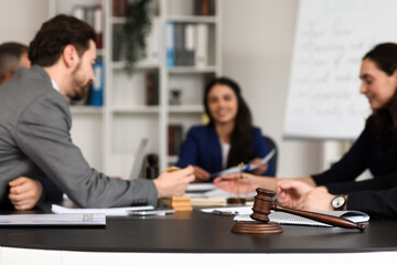 Judge's gavel on table of lawyers working in office, closeup