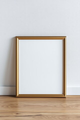 Gold mock up poster frame on the wooden floor by the wall