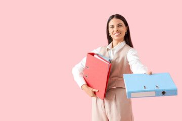 Young businesswoman with folders on pink  background