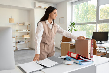Young businesswoman with folders at workplace