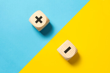 Concept of contrast, opposites, pros and cons with wood block plus and minus sign on blue and...