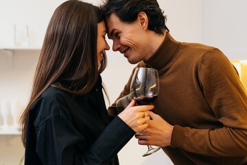 Romantic couple sharing a moment with wine in a cozy indoor setting