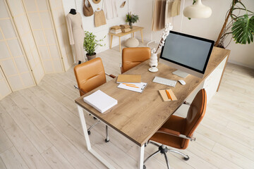 Workplace with blank computer monitor in clothing store office