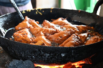 Bread pakora is being fried in hot oil. It is made by stuffing the bread with potatoes and dipping it in the batter of chickpea flour and then frying it. popular snack of India. Indian street food. 
