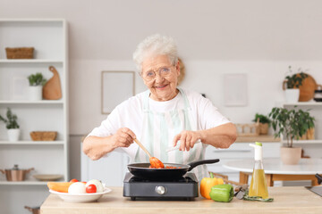 Senior woman salting fried food in kitchen